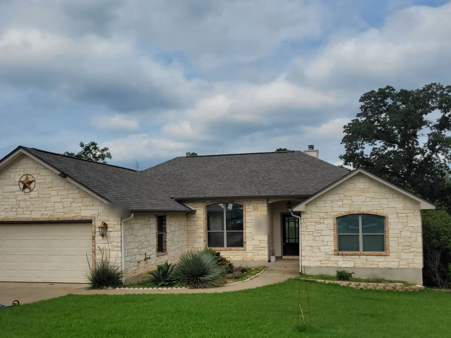 Finished dark gray shingle roof on a single-story limestone ranch home
